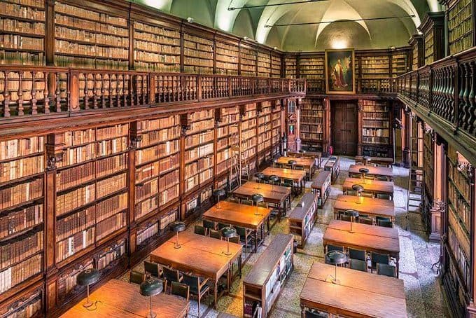 Antica biblioteca con scaffali di libri e tavoli di legno