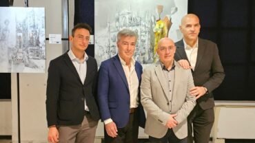 Quattro uomini in abito formale accanto a quadri