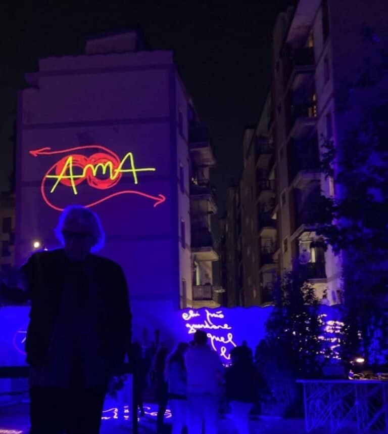 Uomo con insegne al neon AMA su edificio