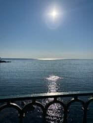 Sole riflette sul mare con ringhiera in primo piano