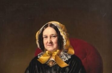 Donna in abito nero e foulard giallo su poltrona rossa