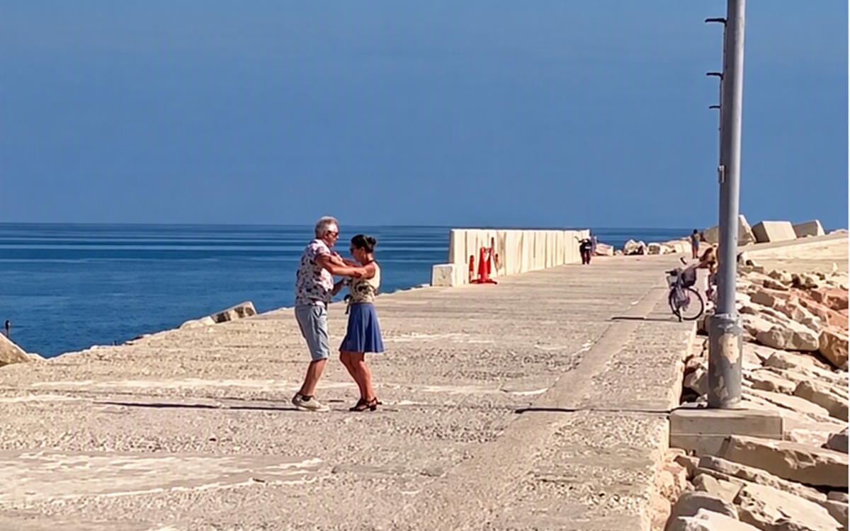 Coppia danza sul molo davanti al mare