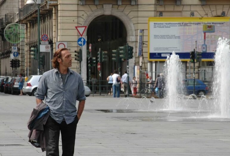 Uomo cammina vicino fontana in città europea