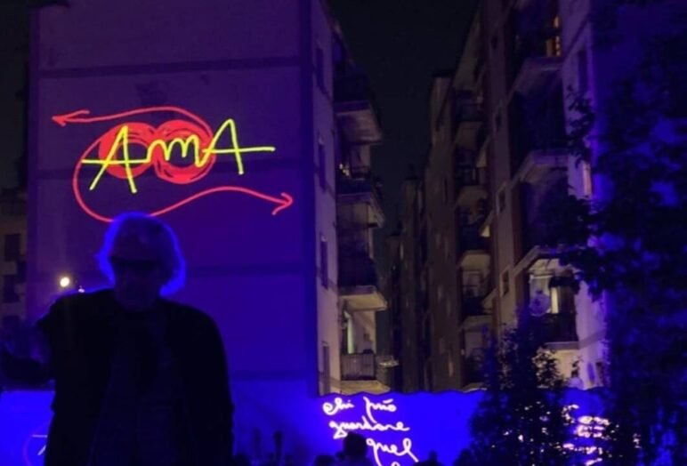 Uomo con insegne al neon AMA su edificio