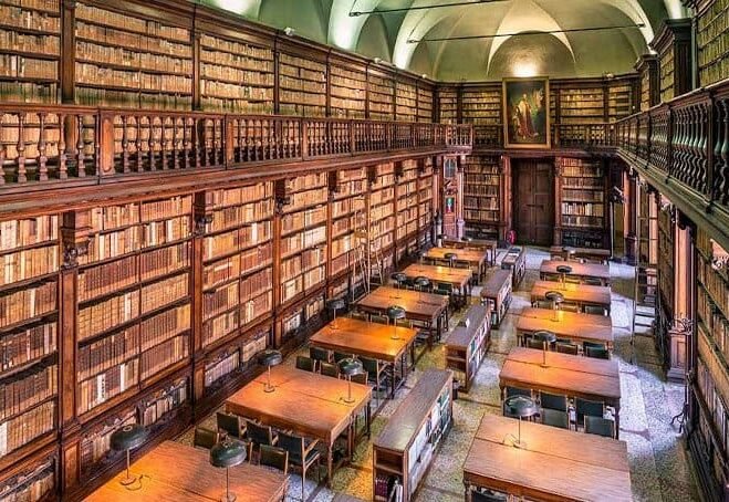 Antica biblioteca con scaffali di libri e tavoli di legno